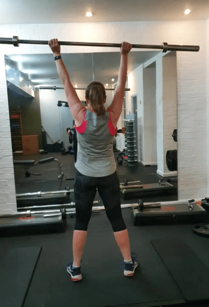 A client performing a fitness exercise with a barbell, showcasing strength and progress during a session at Right Time PT.